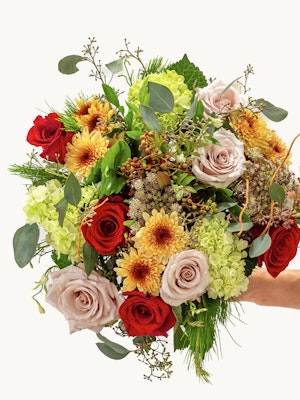 Vibrant floral bouquet featuring red and blush roses with sunflowers and greenery.