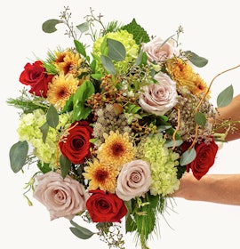 Vibrant floral bouquet featuring red and blush roses with sunflowers and greenery.