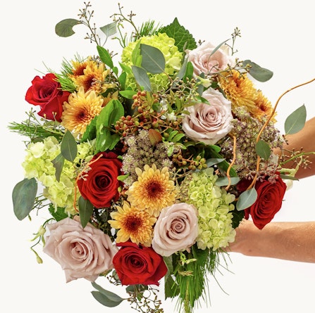 Vibrant floral bouquet featuring red and blush roses with sunflowers and greenery.