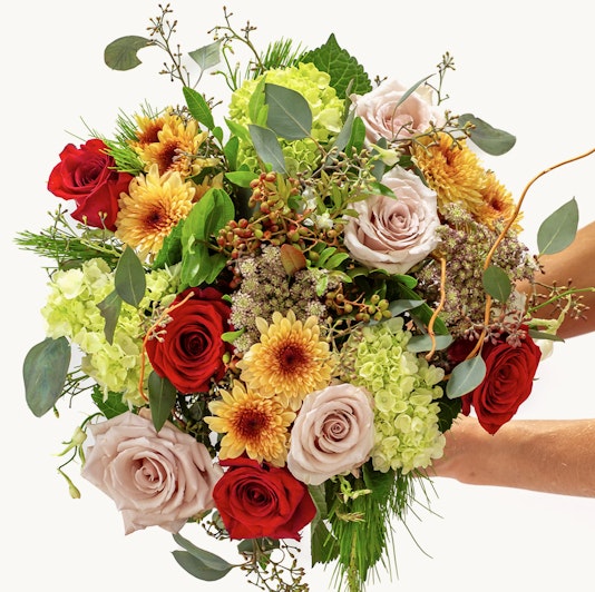 Vibrant floral bouquet featuring red and blush roses with sunflowers and greenery.