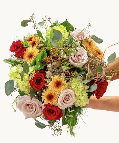 Vibrant floral bouquet featuring red and blush roses with sunflowers and greenery.