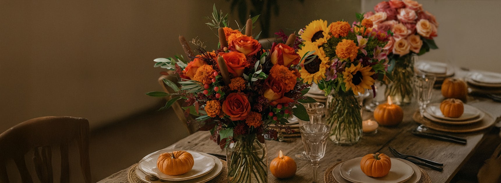 A charming autumnal dining table adorned with vibrant floral arrangements and pumpkins.