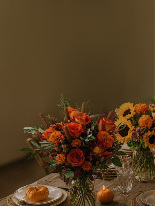 Elegant autumn bouquet featuring orange roses, marigolds, and sunflowers, perfect for fall decor.
