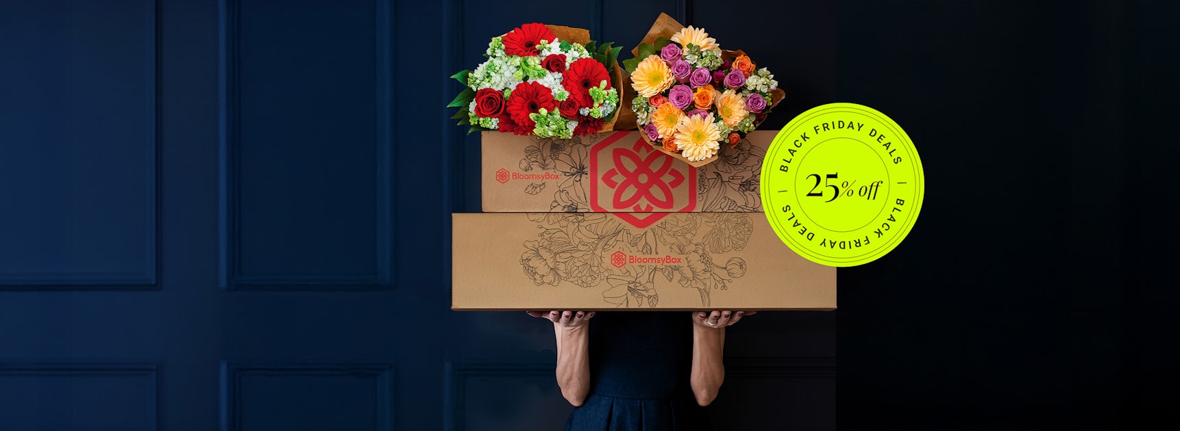 A person holding large floral gift boxes filled with vibrant, multicolored blooms.