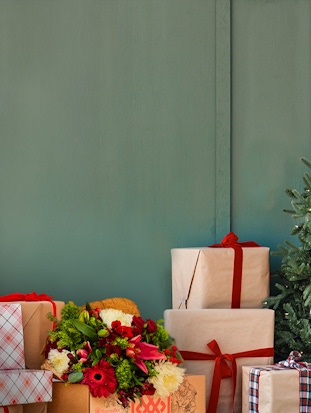 Festively wrapped gifts and a colorful floral arrangement enhance a cozy holiday scene.