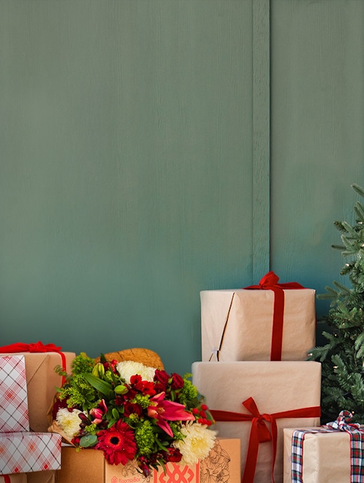 Festively wrapped gifts and a colorful floral arrangement enhance a cozy holiday scene.