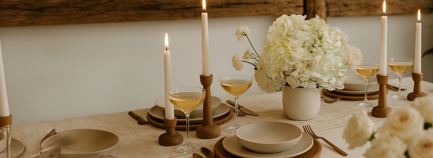 Elegant dining table set with candles, hydrangeas, and chic tableware for special occasions.
