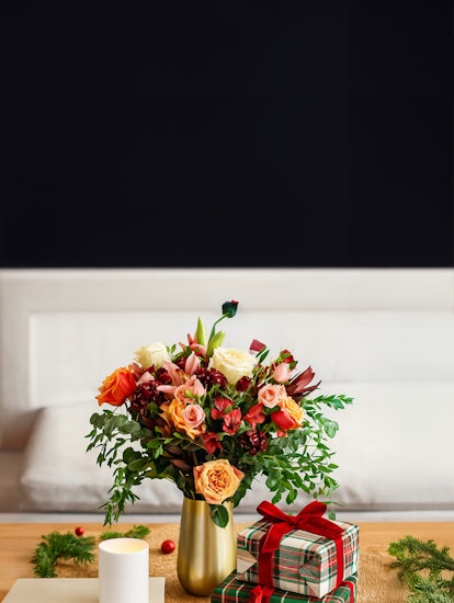 Vibrant flower bouquet with roses and greenery, accented by festive gift boxes.