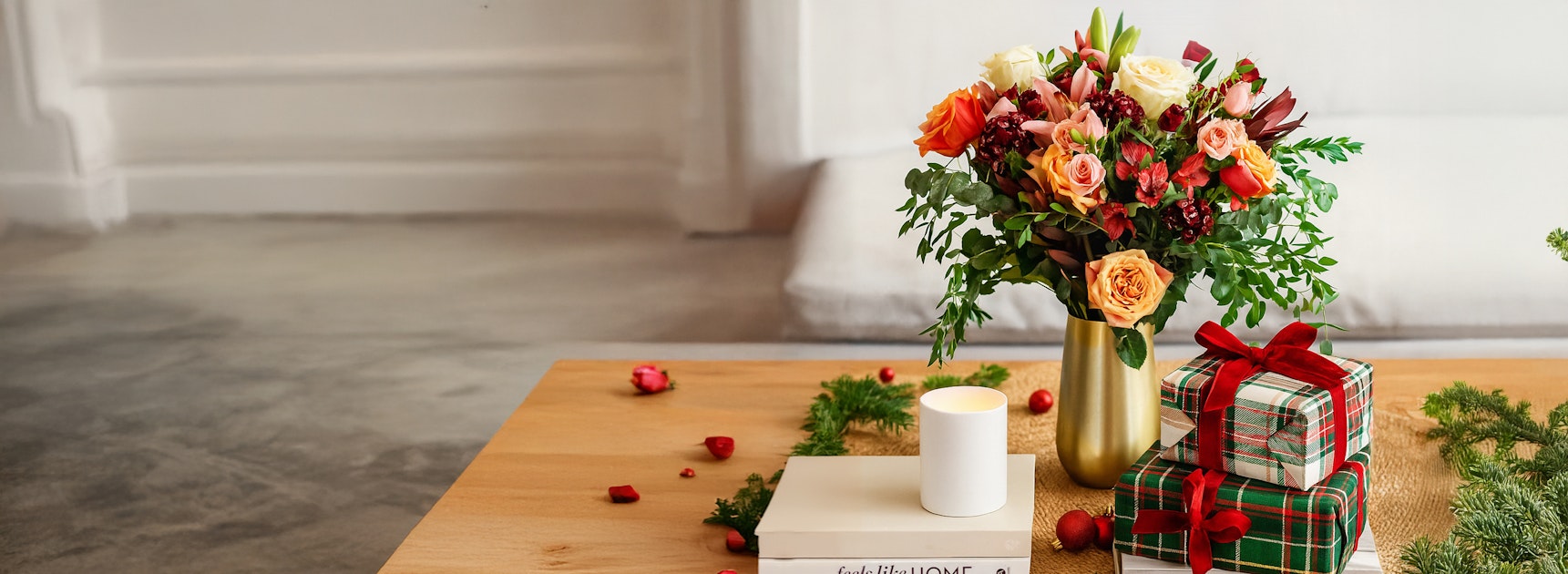 Vibrant floral arrangement with roses and greenery, beautifully staged with gifts and candles.