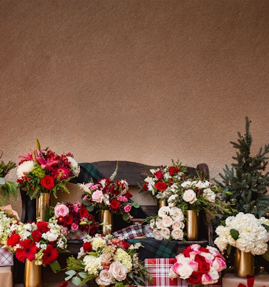 A vibrant display of assorted floral bouquets in festive arrangements on a rustic bench.