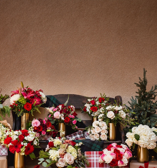 A vibrant display of assorted floral bouquets in festive arrangements on a rustic bench.