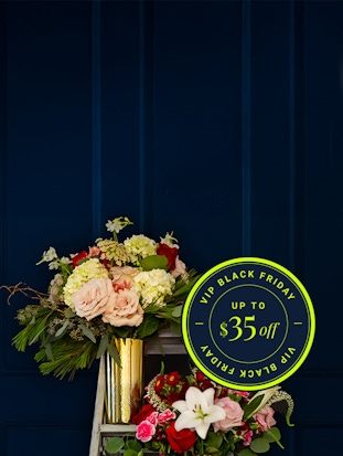 Beautiful floral arrangement featuring roses, hydrangeas, and seasonal blooms, adorned with a Black Friday sale sign.