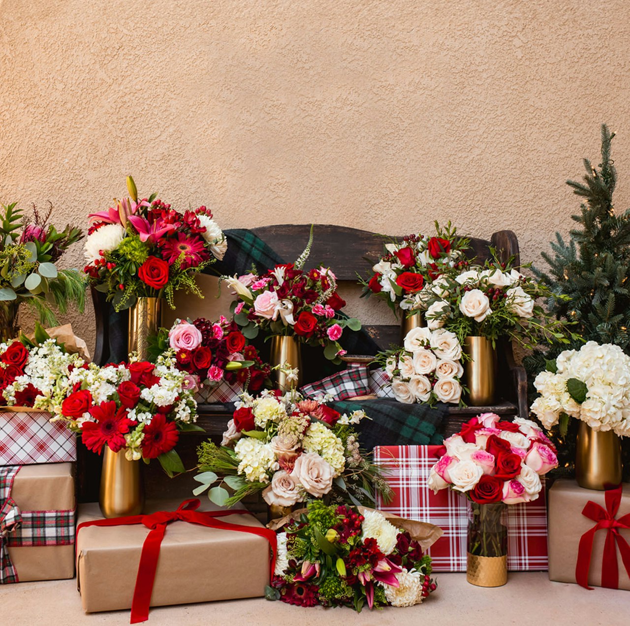 Festive floral arrangements in elegant vases surrounded by beautifully wrapped gifts.