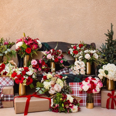 Festive floral arrangements in elegant vases surrounded by beautifully wrapped gifts.