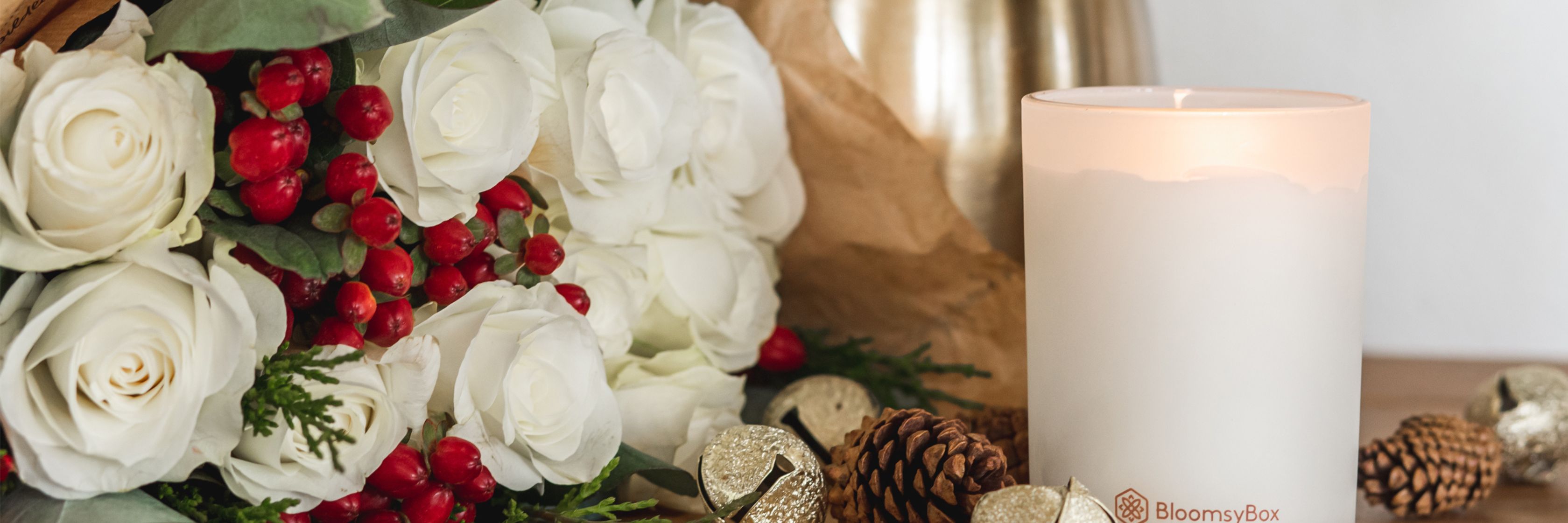 Elegant white rose bouquet with red berries and festive decor elements.
