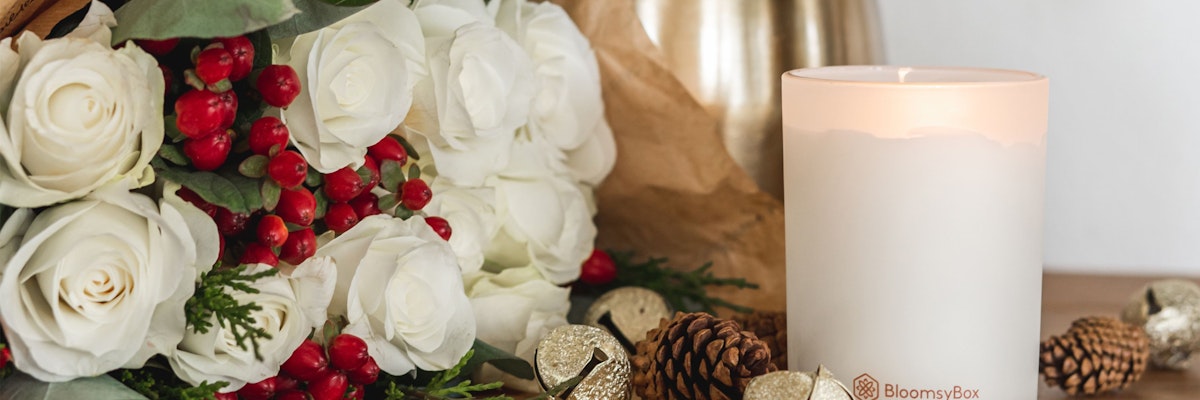 Elegant white rose bouquet with red berries and festive decor elements.