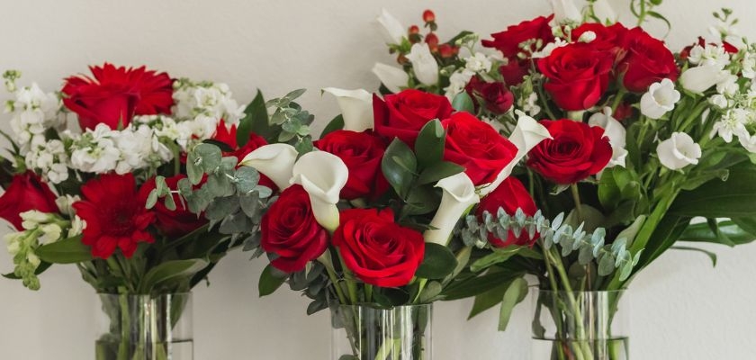 Beautiful floral arrangement featuring red roses, white calla lilies, and lush greenery.