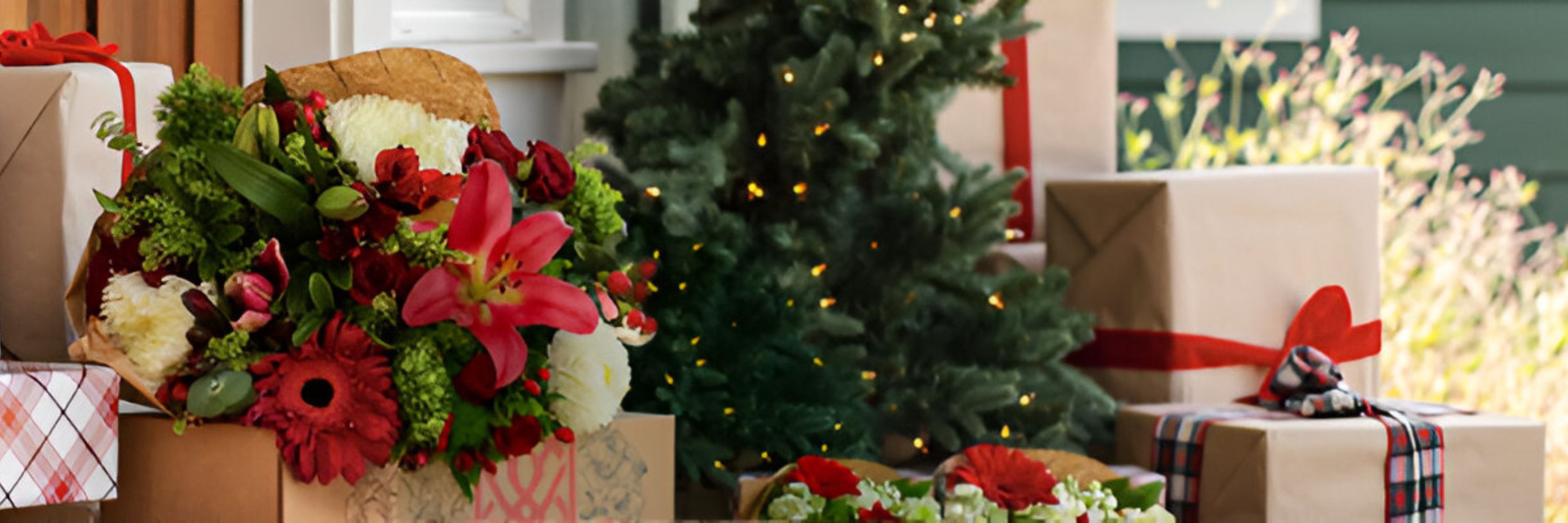 Vibrant holiday floral arrangement with gifts and a festive backdrop of lights.