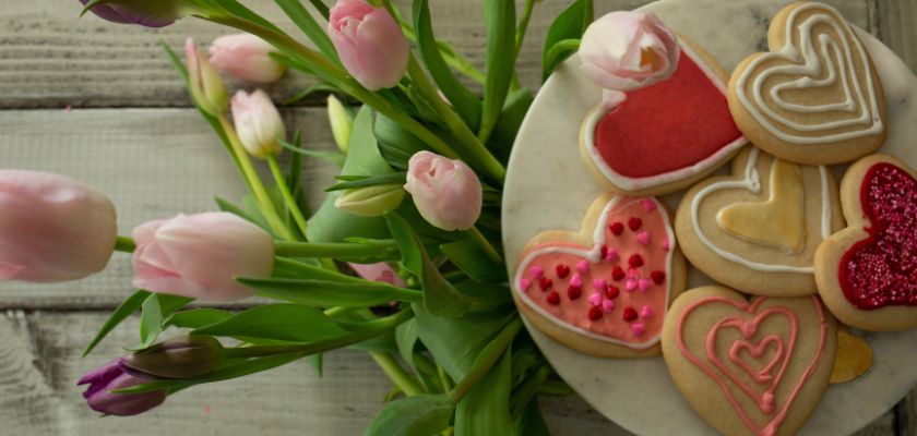 Heart-shaped cookies decorated with icing, paired with beautiful pink tulips.