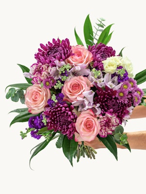 Vibrant bouquet featuring pink roses, purple chrysanthemums, and green accents, elegantly arranged.