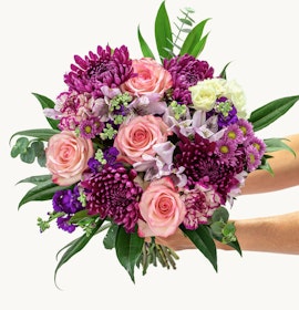 Vibrant bouquet featuring pink roses, purple chrysanthemums, and green accents, elegantly arranged.