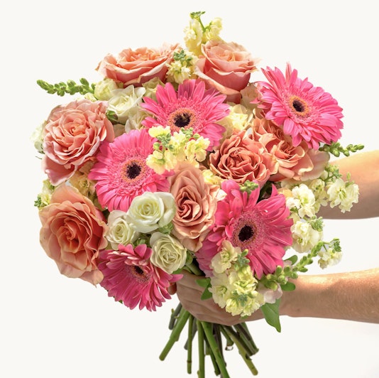 Blooming floral bouquet featuring pink gerbera daisies, roses, and delicate white blooms.