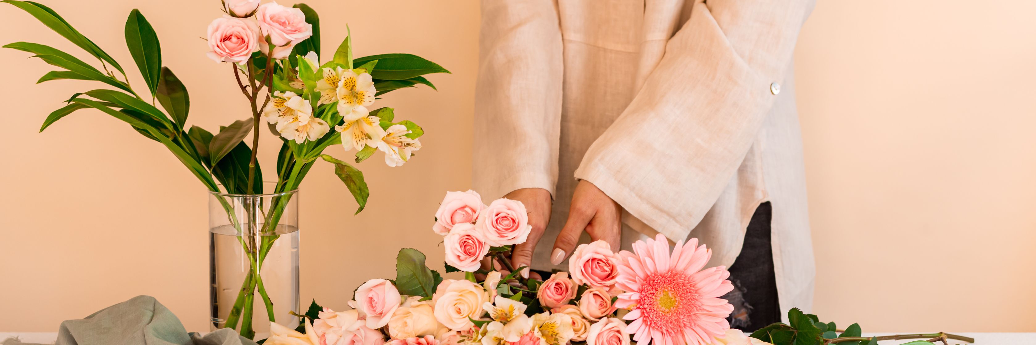 A person arranging a beautiful floral bouquet with pink roses and white flowers.