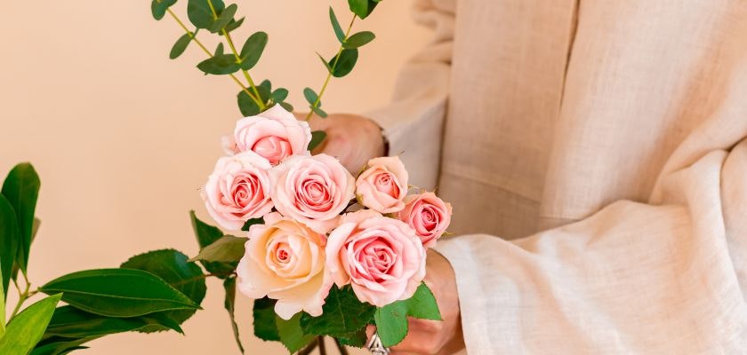 Delicate pink rose bouquet held by a person in soft fabric, perfect for any occasion.