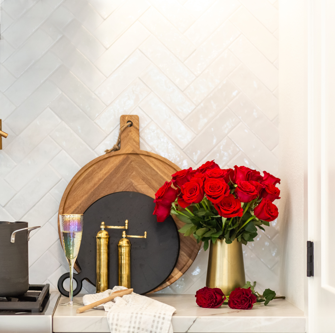 Vibrant red roses in a golden vase, adding elegance to a stylish kitchen setting.