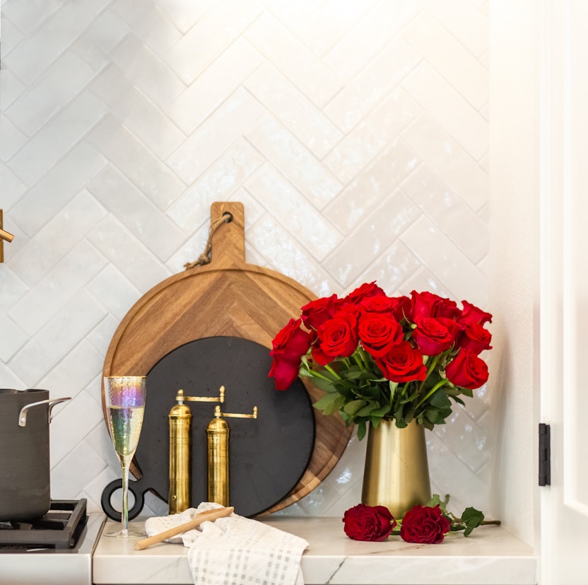 Vibrant red roses in a golden vase, adding elegance to a stylish kitchen setting.