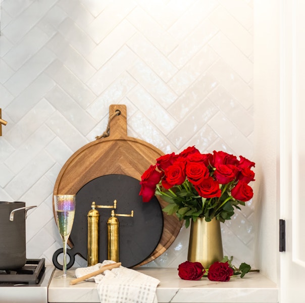 Vibrant red roses in a golden vase, adding elegance to a stylish kitchen setting.