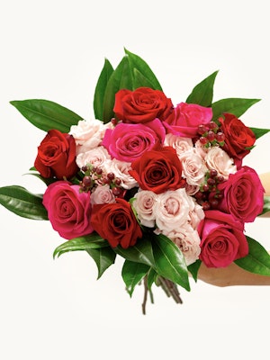 Vibrant rose bouquet featuring deep red, soft pink, and bold magenta blooms with lush greenery.
