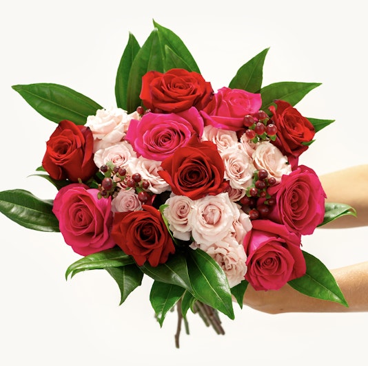 Vibrant rose bouquet featuring deep red, soft pink, and bold magenta blooms with lush greenery.