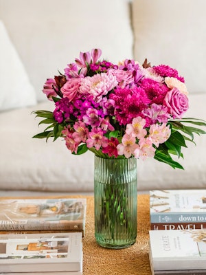 Vibrant mixed flower bouquet with pink roses, daisies, and alstroemeria in a glass vase.