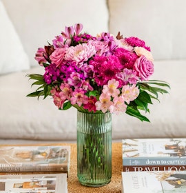 Vibrant mixed flower bouquet with pink roses, daisies, and alstroemeria in a glass vase.