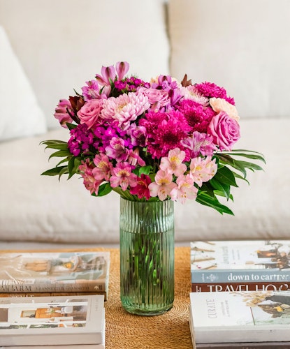 Vibrant mixed flower bouquet with pink roses, daisies, and alstroemeria in a glass vase.