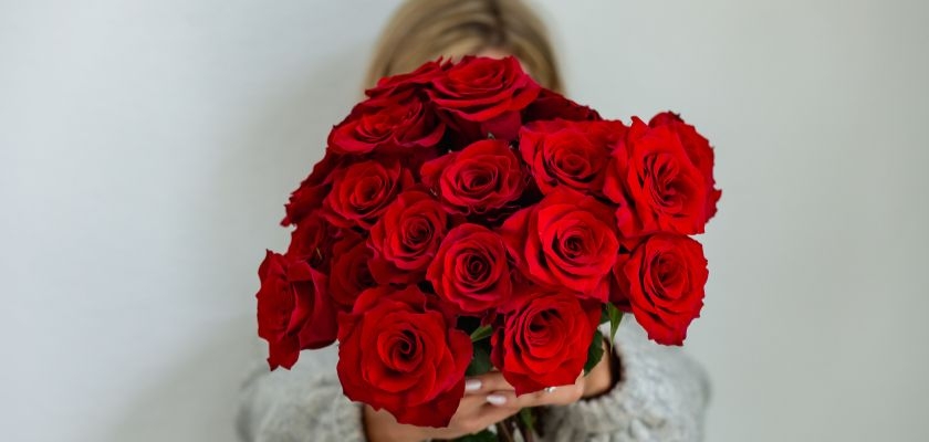A beautiful bouquet of vibrant red roses held by a person, symbolizing love and affection.