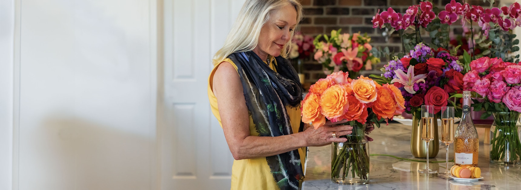 A woman admiring a vibrant bouquet of orange roses in a stylish floral shop setting.