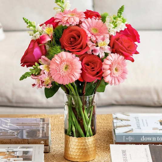 Vibrant floral arrangement featuring pink gerberas, red roses, and bright blooms in a stylish vase.