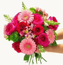 Vibrant bouquet featuring pink roses, gerbera daisies, and colorful florals in hand.