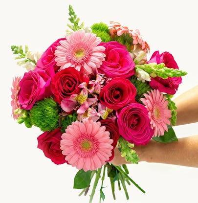 Vibrant bouquet featuring pink roses, gerbera daisies, and colorful florals in hand.