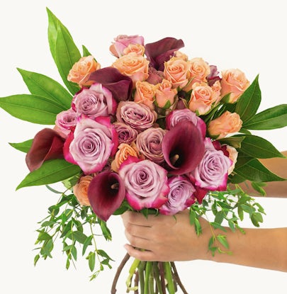 Vibrant bouquet featuring pink and peach roses with elegant calla lilies and lush greenery.