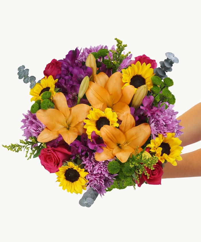 Vibrant bouquet featuring orange lilies, sunflowers, and purple blooms, ideal for celebrations.