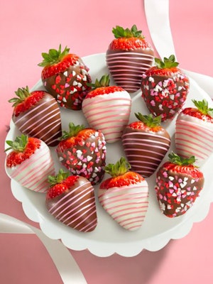A delightful platter of chocolate-covered strawberries decorated with festive sprinkles.