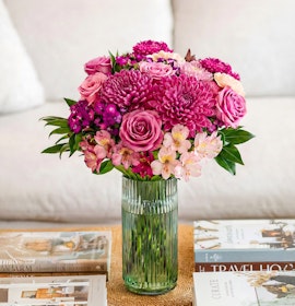 Vibrant pink bouquet featuring roses, chrysanthemums, and orchids in a stylish vase.