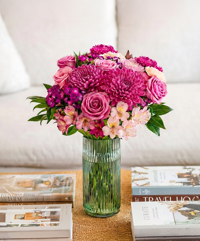Vibrant pink bouquet featuring roses, chrysanthemums, and orchids in a stylish vase.