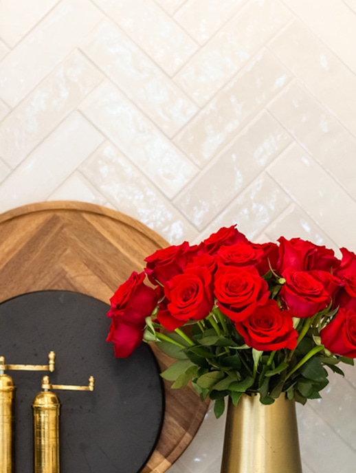 Vibrant red roses elegantly arranged in a gold vase against a stylish backdrop.