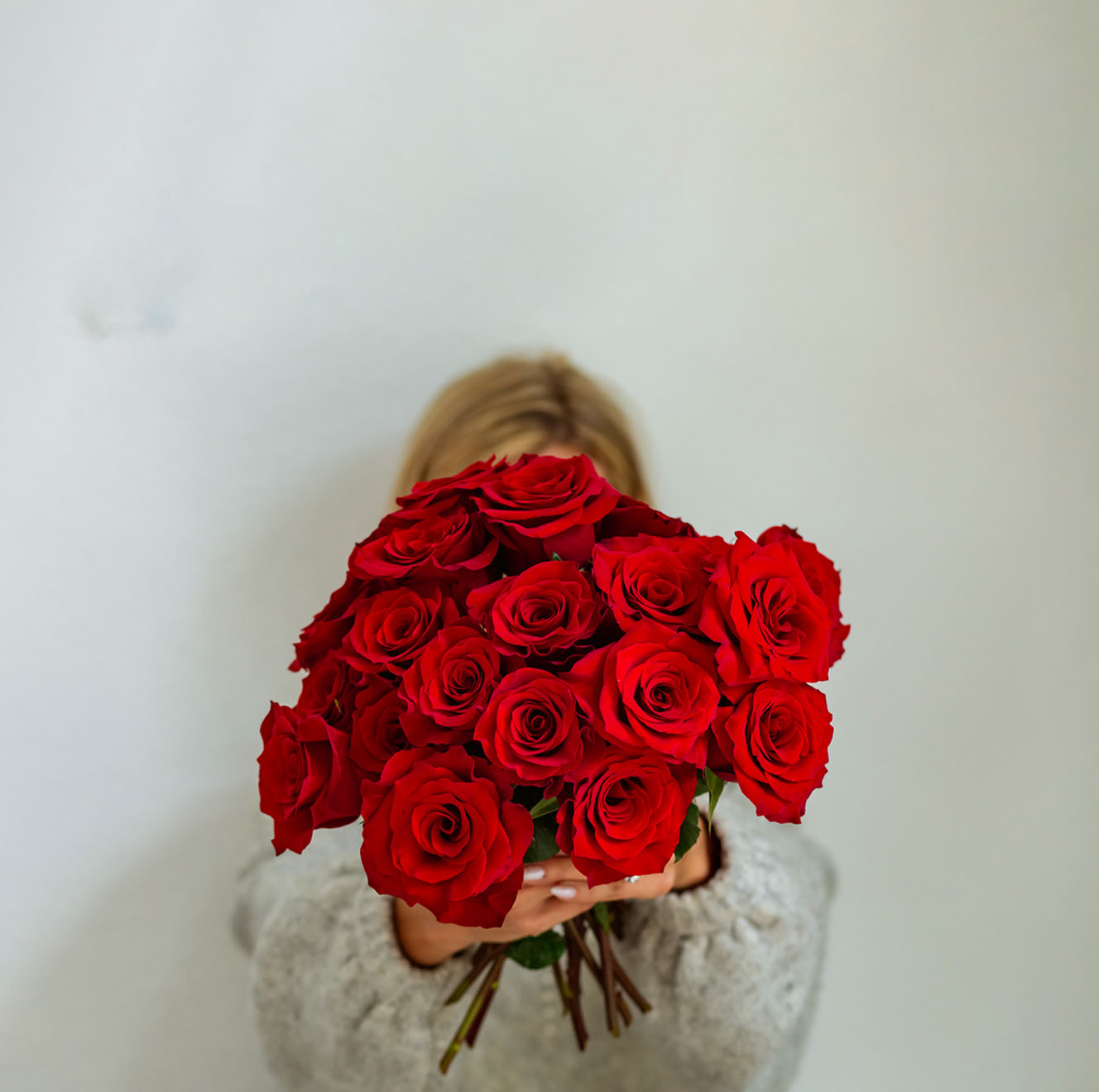 A vibrant bouquet of red roses held by a person, perfect for expressing love and affection.