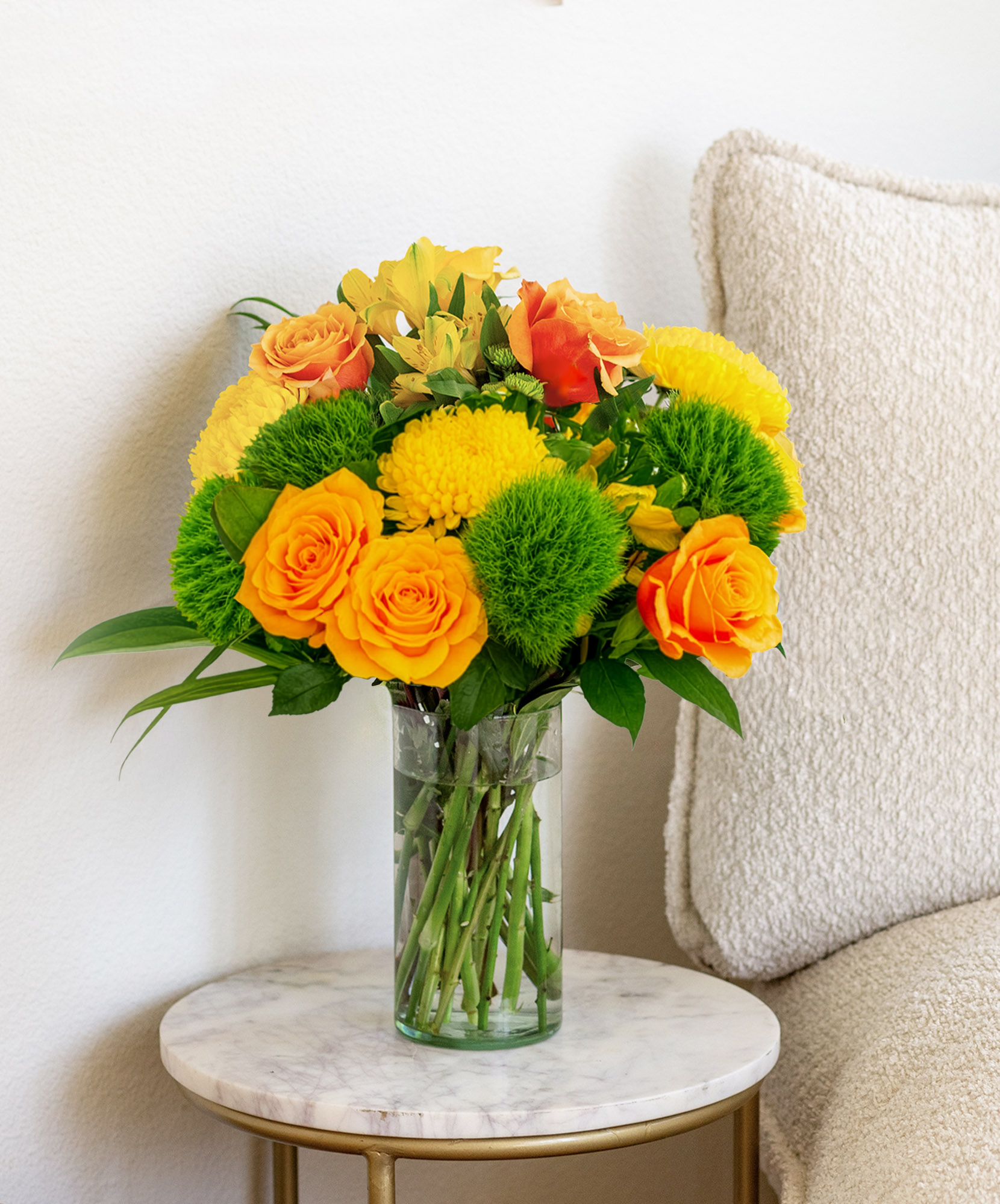 Vibrant yellow and orange flower bouquet in a glass vase, perfect for brightening any room.