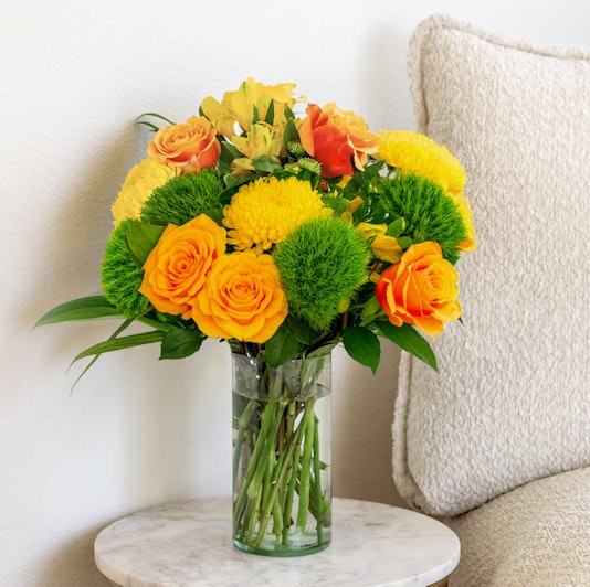 Vibrant yellow and orange flower bouquet in a glass vase, perfect for brightening any room.